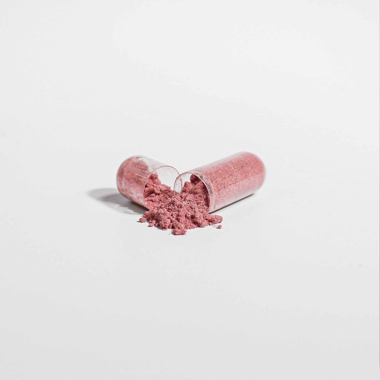Organic beetroot powder capsules split open, revealing vibrant red powder.