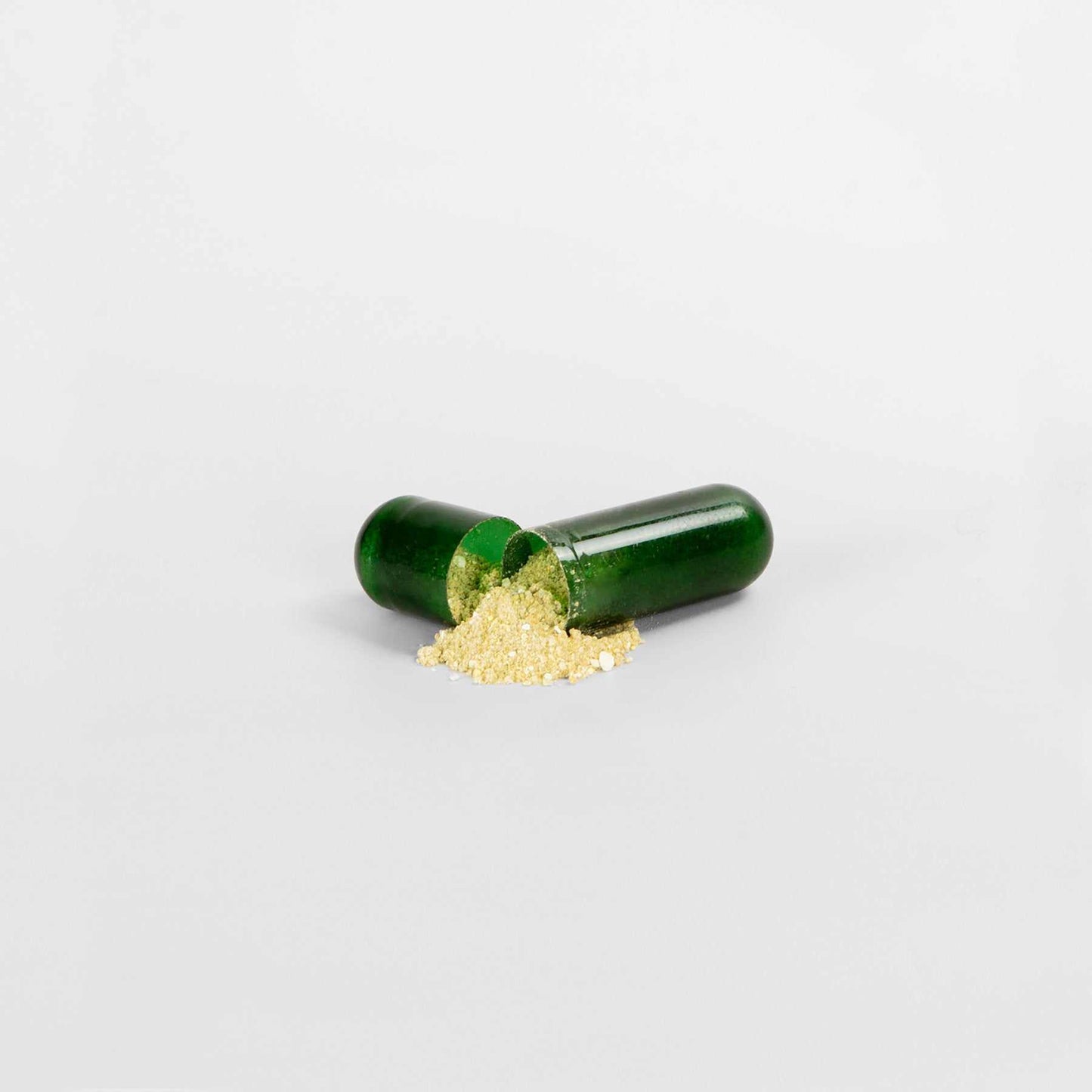 Green capsule split open showing yellow powder, Fat Burner with MCT supplement.