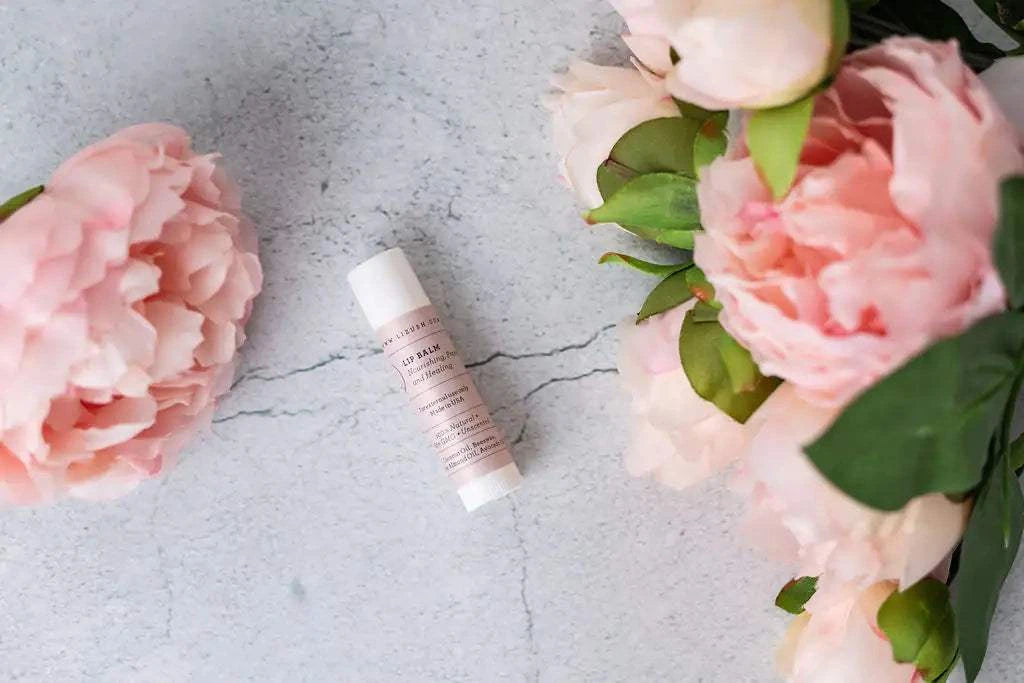 Mother's Day gift featuring a pink unscented lip balm surrounded by pink flowers on a textured background.