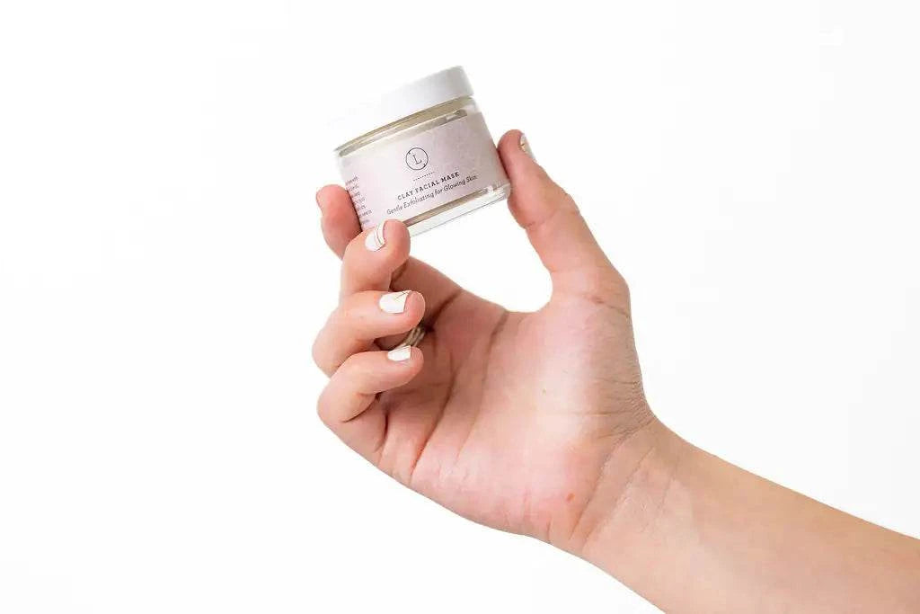 Hand holding a jar of natural lavender clay mask from the spa gift box relaxing package.