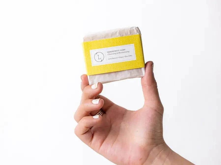 Grapefruit soap bar held in hand, part of a Christmas gift box.