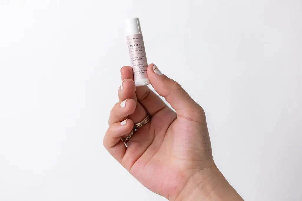 Lip balm held in a hand, part of a pampering natural skincare gift set for new moms.