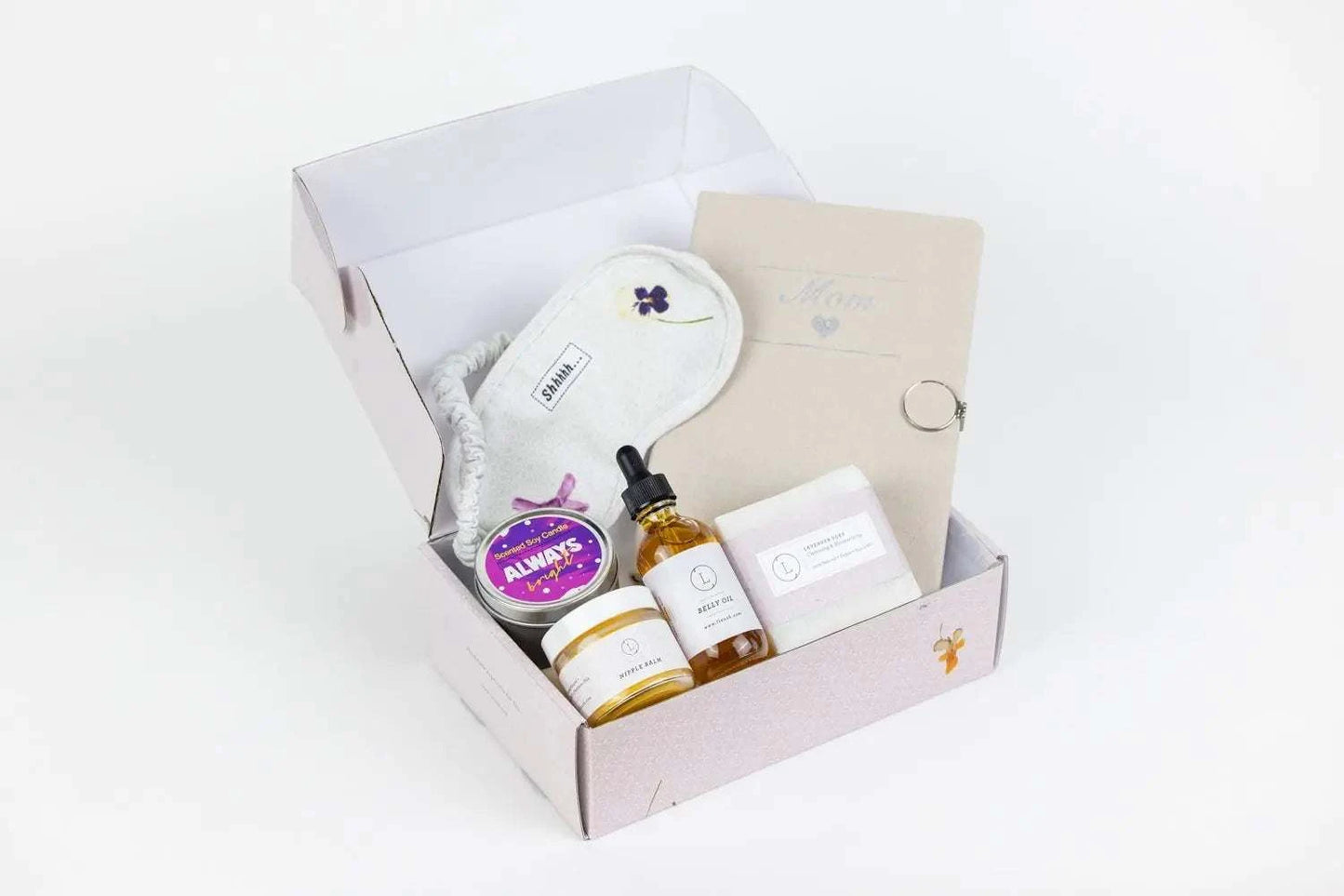 Pregnancy Gift Box with nipple balm, belly oil, scented candle, journal, lavender soap, and cotton eye mask in a personalized box.