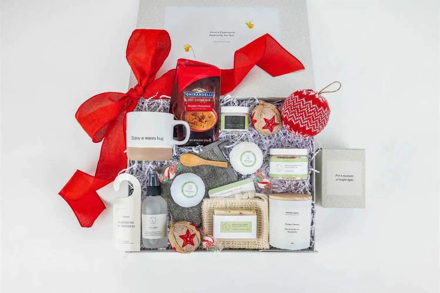 Christmas gift basket with ceramic mug, scented candle, peppermint candies, eucalyptus bath salts, soap, bath bombs, foot cream, mist, hot cocoa, ornament, and customizable greeting card.