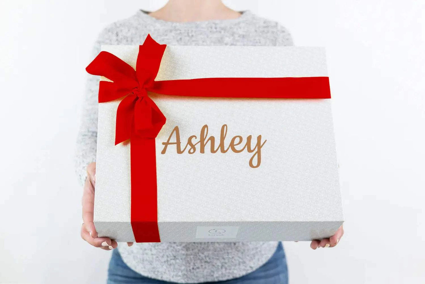 Christmas gift basket with red ribbon, personalized with a name on the lid.