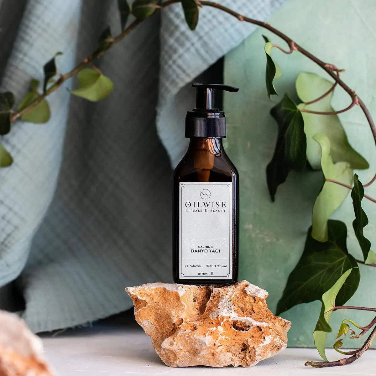 Oilwise Calming Bath Oil 100 ml bottle with natural ingredients displayed on stone.