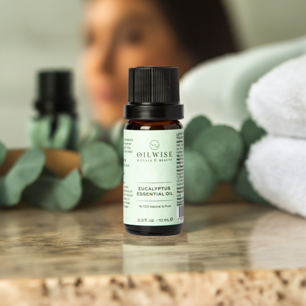 Oilwise Eucalyptus Essential Oil bottle on a bathroom counter with eucalyptus leaves in the background.