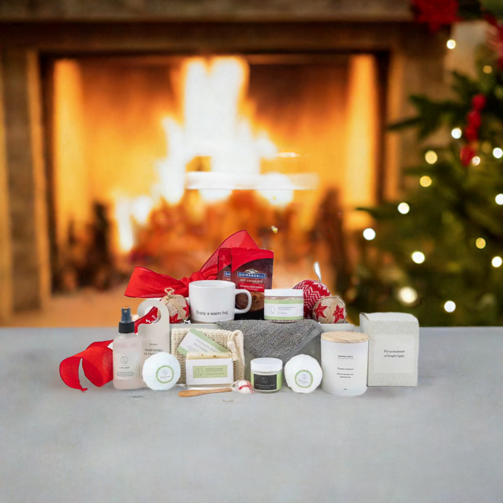 Christmas gift basket with ceramic mug, scented candle, peppermint candies, bath salt, eucalyptus soap, bath bombs, foot cream, mist, hot cocoa, Christmas ornament, and gift box, set in a festive background.