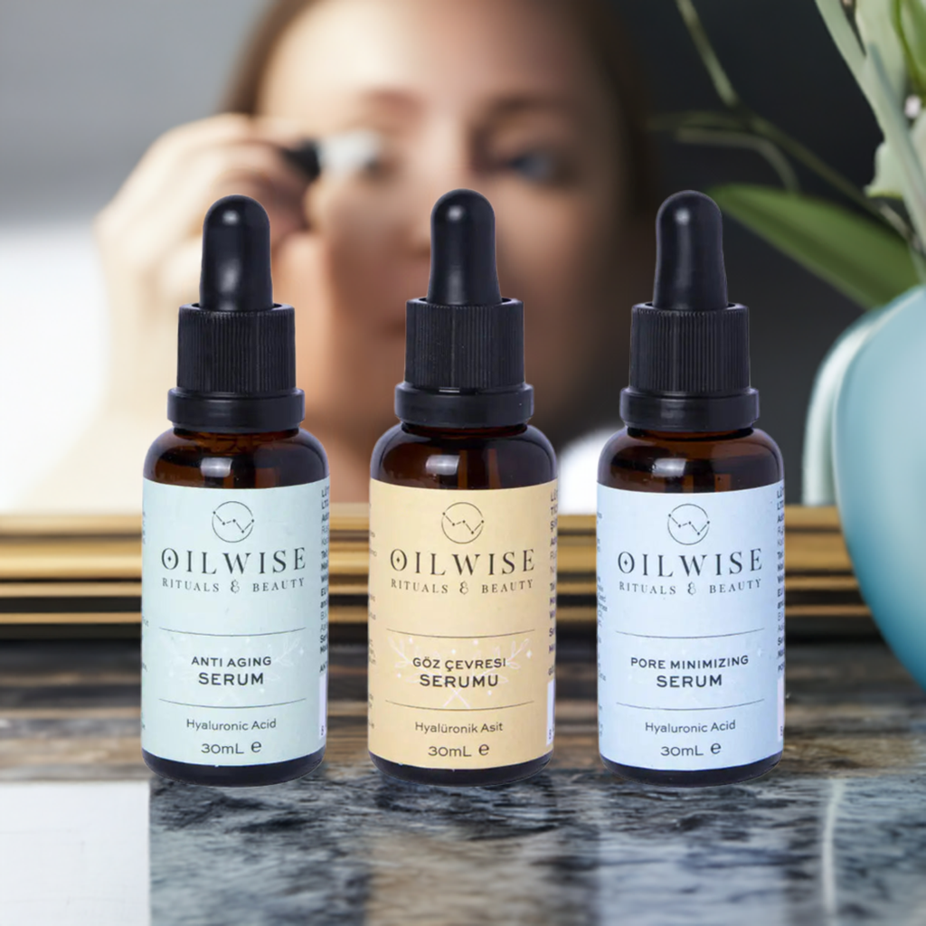 Oilwise Antiaging Serum, Pore Minimizing Serum, Eye Repair Serum set on a marble surface with a blurred background of a person applying makeup.