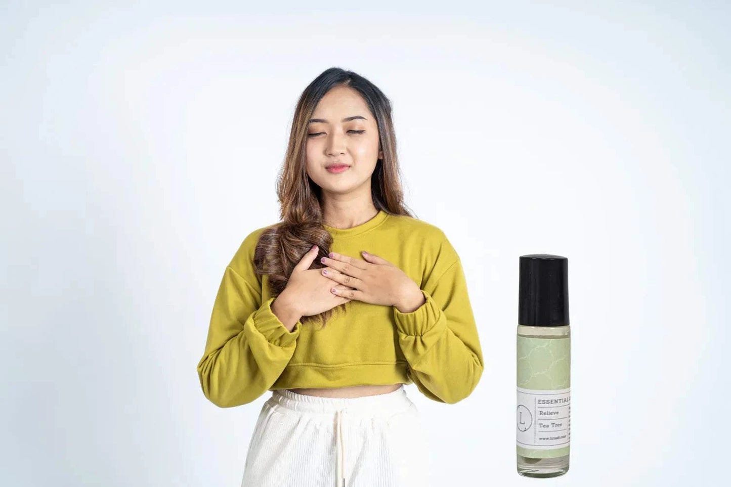 Essential Oils Roll-On Set with Crystals and CBD, featuring a woman in a green top holding her chest, conveying relaxation and self-care.
