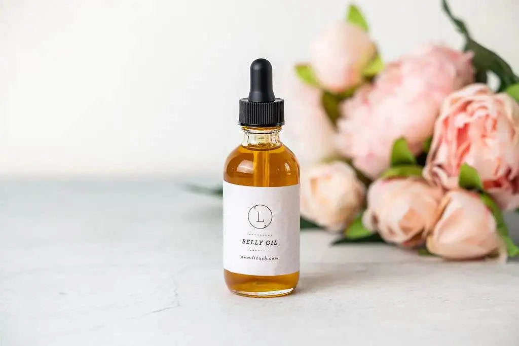 Belly oil bottle from New Mom Pampering Natural Skincare gift set, surrounded by pink flowers.