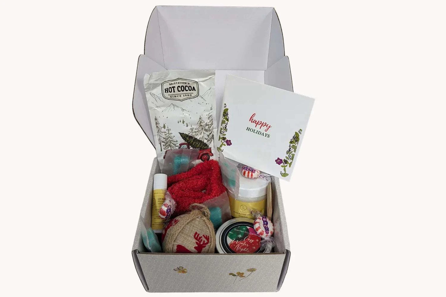 Christmas gift box filled with bath products, red socks, hot cocoa, and a holiday card for cozy nights.
