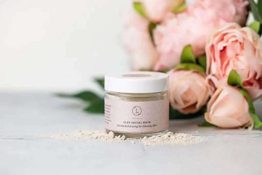 Natural clay facial mask with delicate pink flowers in the background, part of a pampering skincare gift set for new moms.