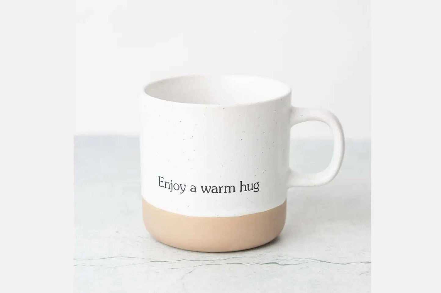 Ceramic mug with "Enjoy a warm hug" text from Christmas gift basket set.