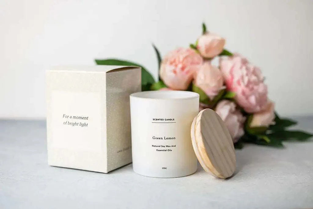 Natural care package featuring a green lemon scented candle and gift box, surrounded by pink flowers.