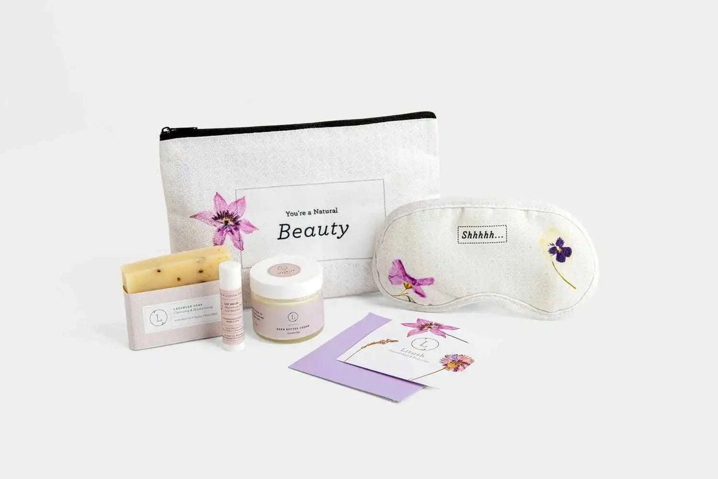 Cosmetic bag bath and body gift set with floral design, featuring lavender products like soap, shea butter, and an eye mask, ideal for travel or appreciation.